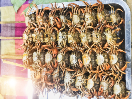Mehrere kleine Krabben, die auf Holzspießen aufgereiht sind und auf einem Metalltablett liegen.